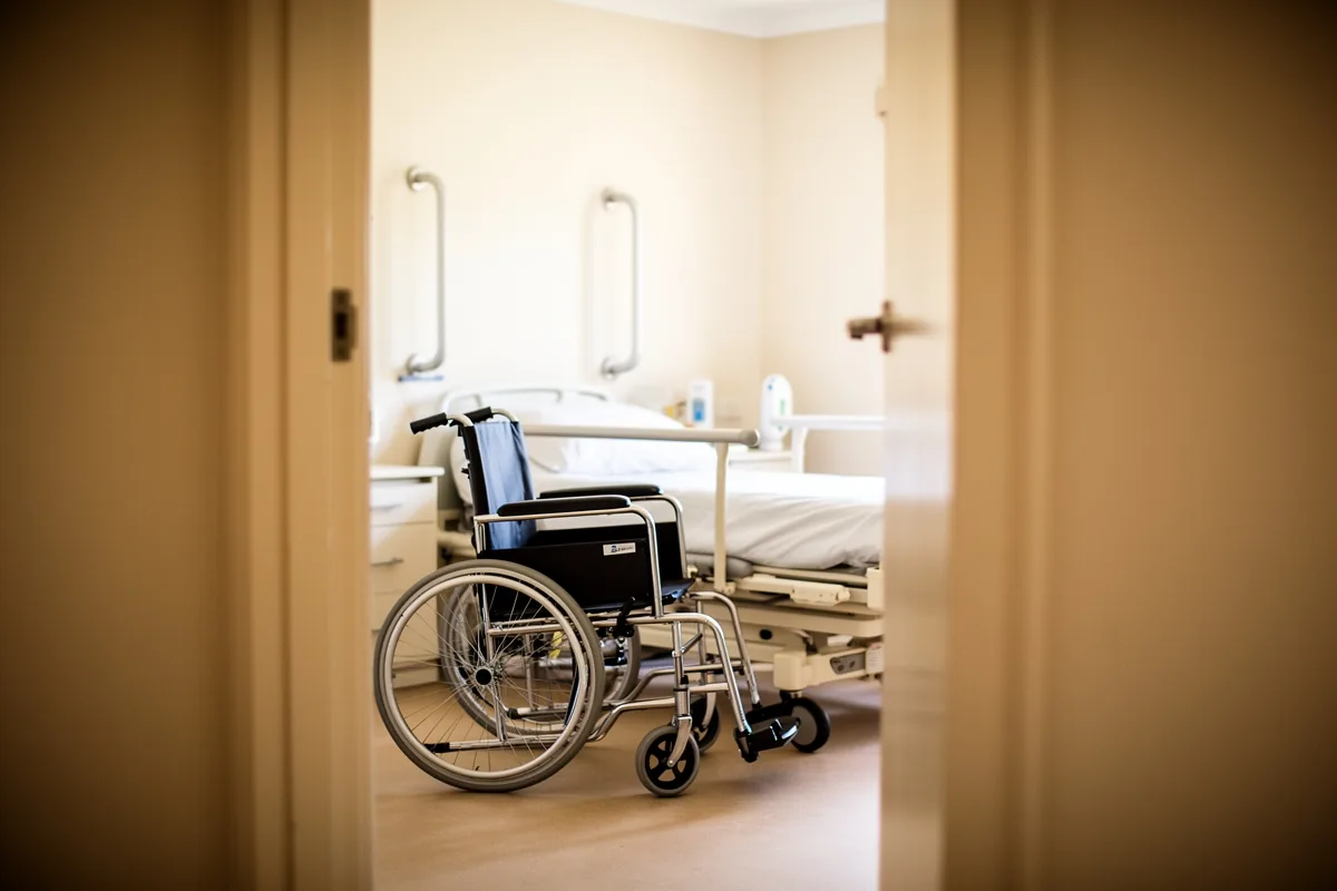An accessible living room in a supported independent living home with clear floor space and a height-adjustable armchair